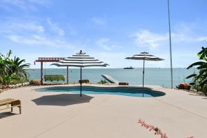 Crystal BeachにあるThe Peach Pelican homeのパラソル2本と海を備えたスイミングプール
