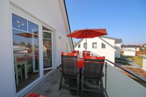 a balcony with a table and chairs and an umbrella at Haus Möwe - Whg 5 in Thiessow