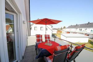 a table and chairs on a balcony with an umbrella at Haus Möwe - Whg 5 in Thiessow