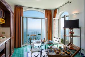 Sala de estar con mesa y vistas al océano en Amalfi Residence, en Conca dei Marini