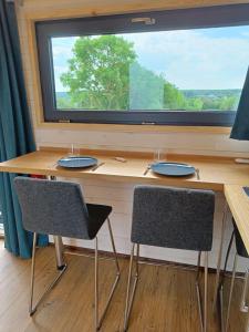 une table avec deux chaises et une grande fenêtre dans l'établissement Tiny Roch', à Rochefort