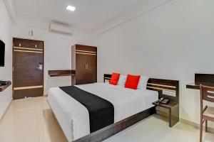 1 dormitorio con 1 cama blanca grande con almohadas rojas en Collection O World Class Hotel Crescent Near Phoenix Marketcity, en Bangalore