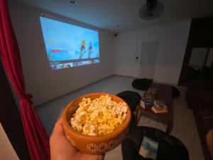 a person holding a bowl of popcorn in front of a television at Hostel Oryx Valladolid in Valladolid
