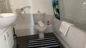 La salle de bains blanche est pourvue de toilettes et d'un lavabo. dans l'établissement Mayfair - Duplex Relocations, à Wakefield