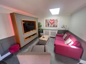 a living room with a pink couch and a tv at Luxury 5* Woodland Retreat, In The Woods. in Skegness