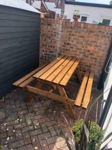 a wooden picnic table sitting next to a brick wall at Chester/Hoole Contemporary Home. Sleeps 6 +Netflix in Chester