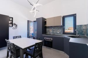 a kitchen with black cabinets and a table with chairs at Residence Medusa by BarbarHouse in Porto Cesareo