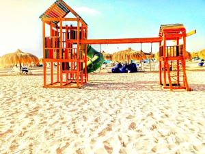 a playground on a sandy beach with umbrellas at شاليه بقرية امواج الساحل الشمالي 3 غرفة Amwaj North Coast in El Alamein