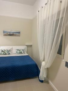 a bedroom with a blue bed and a window with curtains at Le Perle in Maruggio