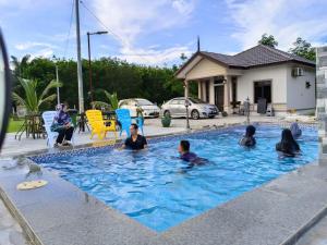 a group of people sitting in a swimming pool at Rumah Armand Private Pool 5 bilik Pengkalan Balak Tg Bidara Masjid Tanah Melaka in Masjid Tanah