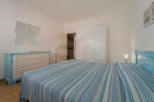 マリーナ・ディ・カンポにあるAppartamenti Maya a Campo - Goelbaのベッドルーム(青いベッド1台、ドレッサー付)