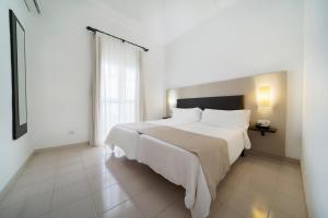 a bedroom with a large white bed and a window at LABRANDA Bahía Fañabé & Villas in Adeje