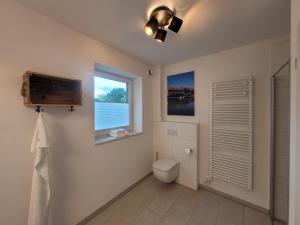Un baño con inodoro y ventana. en Strandkajüte Hooksiel, en Wangerland 23 fotos más