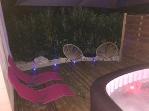 3 sillas y bañera de hidromasaje en una terraza por la noche en LA ROMANTIQUE SPA, en Saint-Avertin