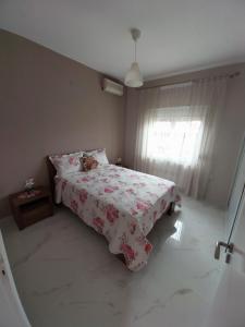 Un dormitorio con una cama con una manta de flores y una ventana en OLGAS no2 HOUSE, en Polígiros