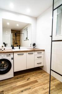 a kitchen with white cabinets and a washer and dryer at UROCZYSKO-POLAŃCZYK Prywatne Jacuzzi i Sauna w cenie !!! in Polańczyk