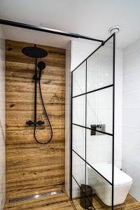 a shower in a bathroom with a wooden wall at UROCZYSKO-POLAŃCZYK Prywatne Jacuzzi i Sauna w cenie !!! in Polańczyk