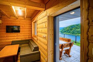 Cabaña de madera con balcón con mesa y ventana en UROCZYSKO-POLAŃCZYK Prywatne Jacuzzi i Sauna w cenie !!! en Polańczyk