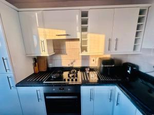 a kitchen with white cabinets and a stove top oven at 3 bed Sky apartment SE15 Peckham in London