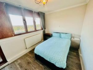 a bedroom with a bed with blue sheets and a window at 3 bed Sky apartment SE15 Peckham in London