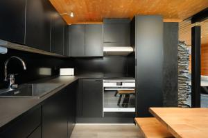 eine Küche mit schwarzen Schränken und einem Holztisch in der Unterkunft Villa Särkkä in Kalajoki