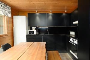 une cuisine avec des armoires noires et une table en bois dans l'établissement Villa Särkkä, à Kalajoki