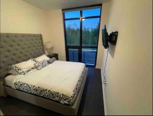 1 dormitorio con cama y ventana grande en Lake Escape, en Innisfil