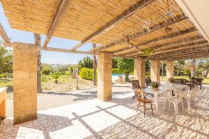 un patio con mesa y sillas bajo una pérgola de madera en Villa dell'edera en Melissano