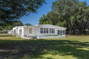 a white house on a grassy field with trees at Nature Lover's Paradise. in Zephyrhills