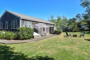 een huis met een achtertuin met een terras en een paraplu bij Beach House Short Walk to Kingsbury Beach in Eastham