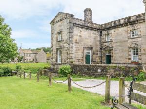 an old stone house with a chain fence in front of it at Sandy Cottage in Linton