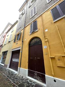 un bâtiment jaune avec deux portes dans une rue dans l'établissement Maison Vert appartamento in centro storico a Modena, à Modène