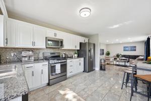 una cocina con armarios blancos y electrodomésticos de acero inoxidable en Charming Contemporary Family Home home, en Glenview