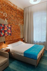 a bedroom with a bed and a brick wall at Hotel Tobaco Łódź in Łódź