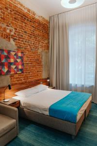 een slaapkamer met een bed en een bakstenen muur bij Hotel Tobaco Łódź in Łódź