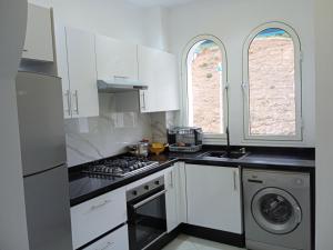 een keuken met witte kasten en een fornuis met oven bij Résidence lilia jabal mdiq in M'diq
