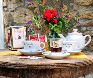 una mesa con tazas y platos de té y un jarrón de flores en Locanda Prato d'Era, en Volterra
