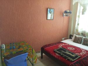 a small bedroom with a bed and a table at Mona Lisa Guest House, Kisumu in Kisumu