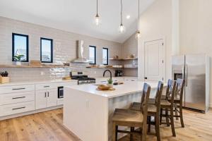 une cuisine avec des placards blancs et un îlot avec des chaises dans l'établissement Desert Bungalow #H8 home, à Hurricane