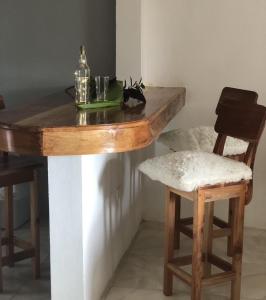 a wooden table with two chairs and a table with a bottle at Seacret Studios - Cozy Jamaican Retreat apts in Negril