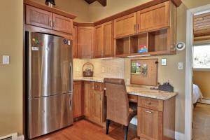 a kitchen with wooden cabinets and a stainless steel refrigerator at Alpine Court Chalet home in Killington