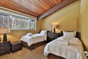 two beds in a bedroom with a wooden ceiling at Alpine Court Chalet home in Killington