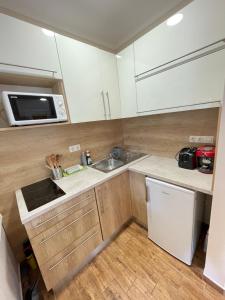 a kitchen with white cabinets and a sink and a microwave at Vadszőlő Apartman in Balatonmáriafürdő