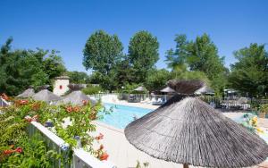 a resort with a pool and some umbrellas at Camping Le Mas de Reilhe in Crespian