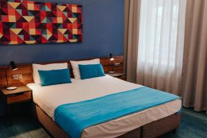 a bedroom with a large bed with blue pillows at Hotel Tobaco Łódź in Łódź