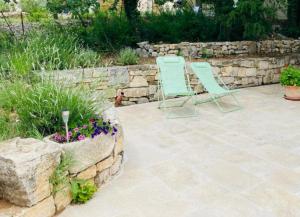 two chairs sitting on a patio with a stone wall at Le Jardin de Pierrefeu in Caseneuve