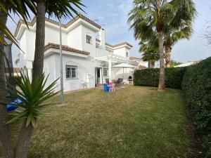 una casa blanca con un patio con palmeras en Casa Rosa en Chiclana de la Frontera