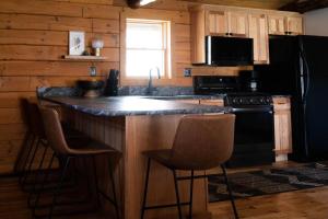 a kitchen with a bar with stools and a black refrigerator at Lake View Cozy Cabin Hocking Hills with Pond and Hot Tub in Rockbridge