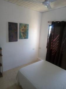 ein Schlafzimmer mit einem Bett und zwei Gemälden an der Wand in der Unterkunft El séptimo día, lugar de descanso in Funes