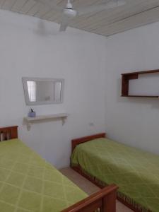two beds in a white room with green sheets at El séptimo día, lugar de descanso in Funes